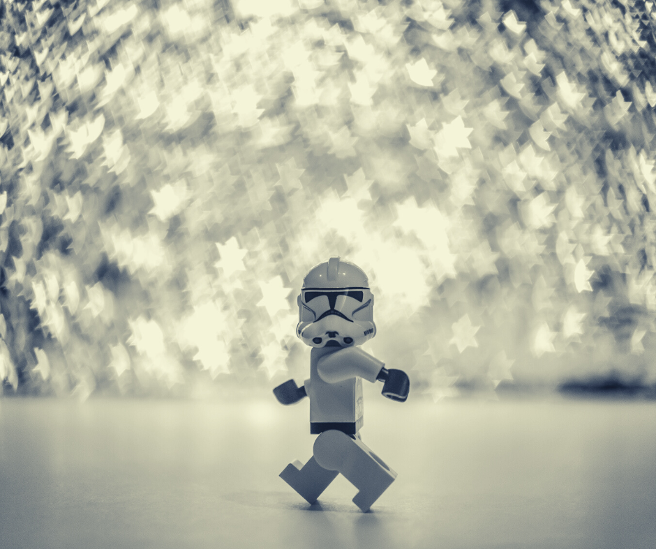 A lego Star Wars figurine in the foreground with glittering silver stars in the background.
